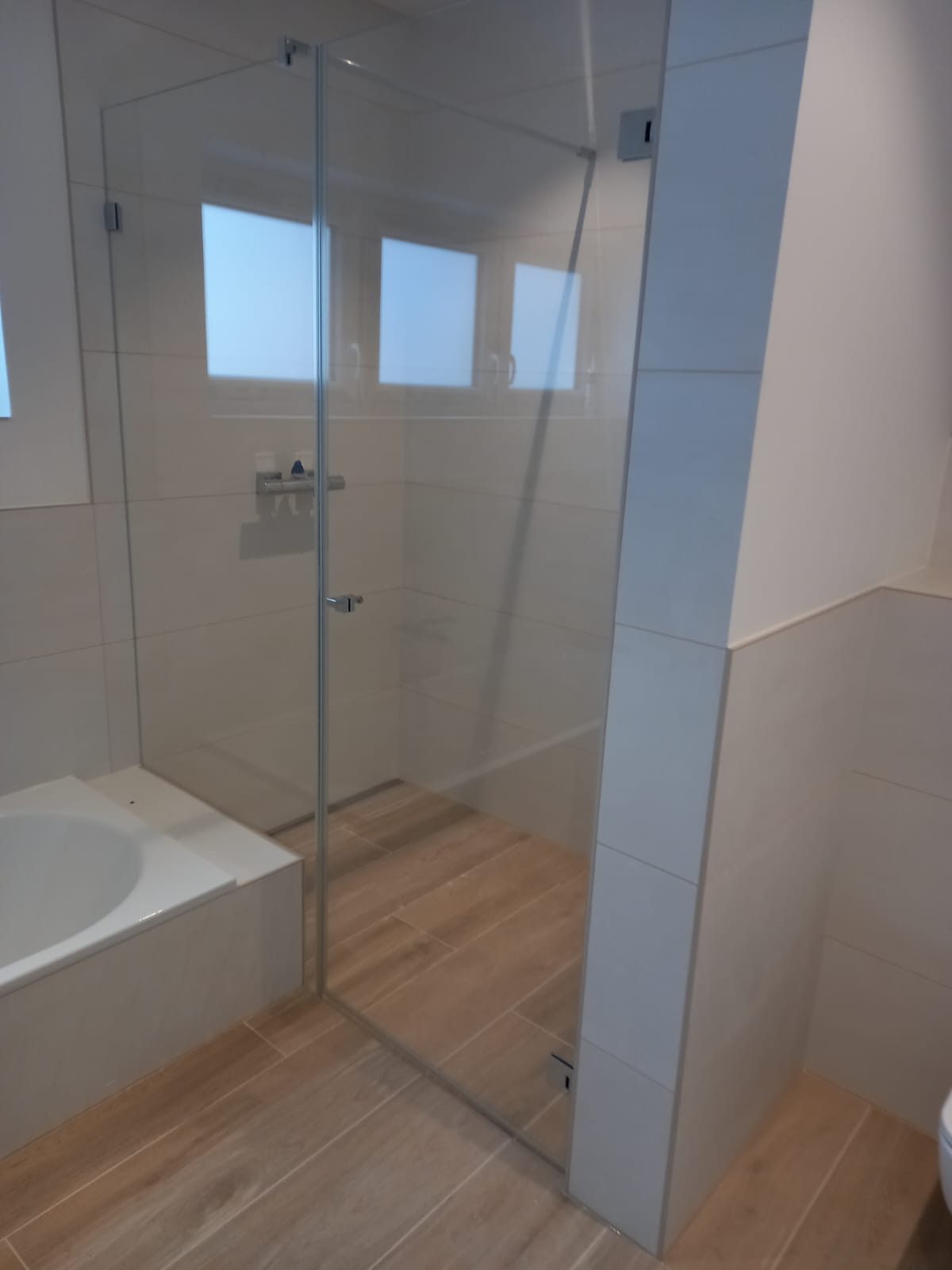 Bodengleiche Dusche mit Glastür, Wandfliesen hell und Boden in Holzoptik